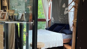 Ein Schlafzimmer mit einem Bett, einem Fenster mit Vorhängen, einem Holzboden und einer Wand mit einem Poster.