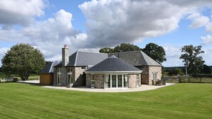 A stone house with a large lawn, a wooden fence, and a clear sky. - Stunning steading conversion (PERTH)