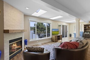 Un salon moderne doté d’une cheminée, de grandes fenêtres et offrant une vue sur un lac.