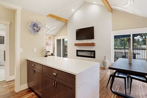 Uma cozinha moderna com uma ilha grande, armários de madeira, lareira e sala de jantar com mesa e cadeiras.
