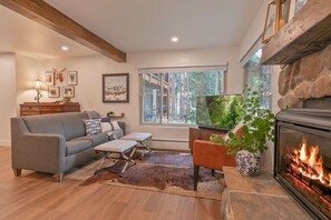Una sala de estar acogedora con chimenea, un sofá, una mesa de centro y un televisor.