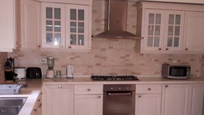 Eine Küche mit weißen Schränken, einem Gasherd, einer Mikrowelle und einem Backofen.