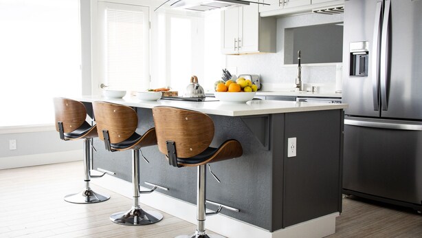 A modern kitchen with a central island, stainless steel appliances, and wooden bar stools. - Contemporary Mountain Home With Panoramic Views (Crestone)