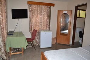 Cozy retreat with a single bed, desk, and TV, plus a bathroom with a toilet and sink.