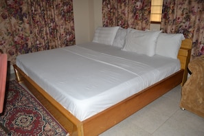 Enjoy a restful stay in this cozy room featuring a single bed, wooden headboard, and neutral-toned decor.