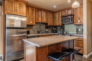 Enjoy cooking in this kitchen with a central island, stainless steel appliances, and wooden cabinetry.