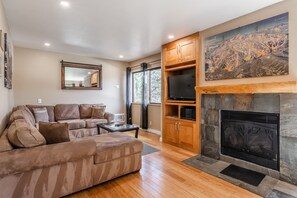 Relax in this inviting living room with a plush sofa, flat-screen TV, and stone fireplace.