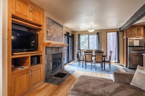 Relax in a warm and inviting space with a stone fireplace, flat-screen TV, and plush sofa.
