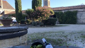 Une variété de légumes frais et une bouteille de vin, le tout disposé en extérieur, avec une église en arrière-plan.