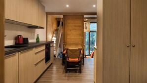 A modern kitchen with wooden cabinets, a dining area with a wooden table and chairs, and a staircase leading to another level.