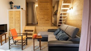 A cozy living room with a wooden interior, a sofa, a chair, a small table, and a TV.