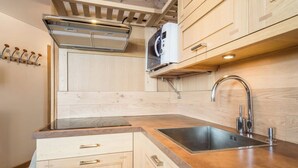 Een moderne keuken met houten kastjes, een roestvrijstalen spoelbak en een ingebouwde magnetron.