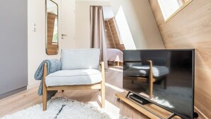 A modern loft bedroom with a sloped ceiling, a large window, a flat-screen TV, a sofa, and a mirror. - Immodreams - Le Mountain Loft - Avoriaz (Avoriaz)