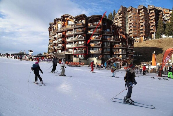 A ski resort with multi-story wooden buildings, ski slopes, and a crowd of skiers.