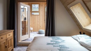 Ein Schlafzimmer mit einem Bett, einer Holzkommode, einem Fenster und einer Tür zu einem Außenbereich.