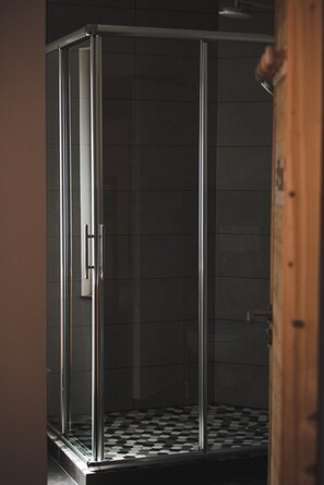 Un espace douche clos par des parois de verre et doté d’un sol carrelé.