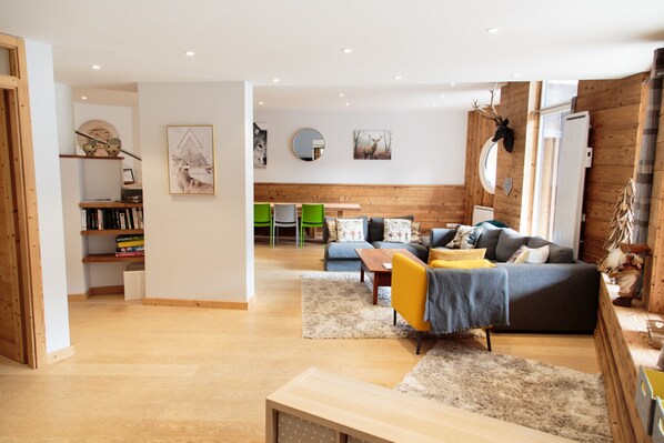 Un salon spacieux avec un plancher en bois, un canapé, une table basse et une bibliothèque.
