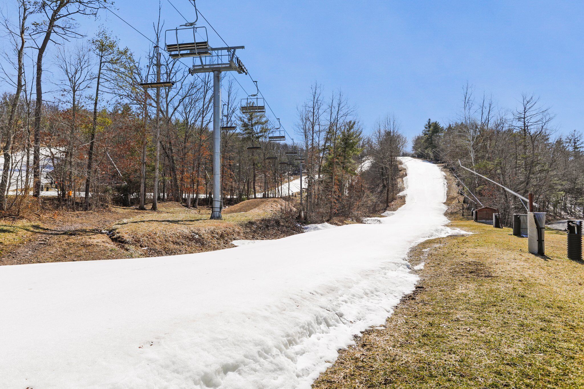 A snowy path with a ski lift and trees.