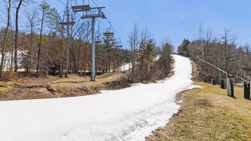 A snowy path with a ski lift and trees.