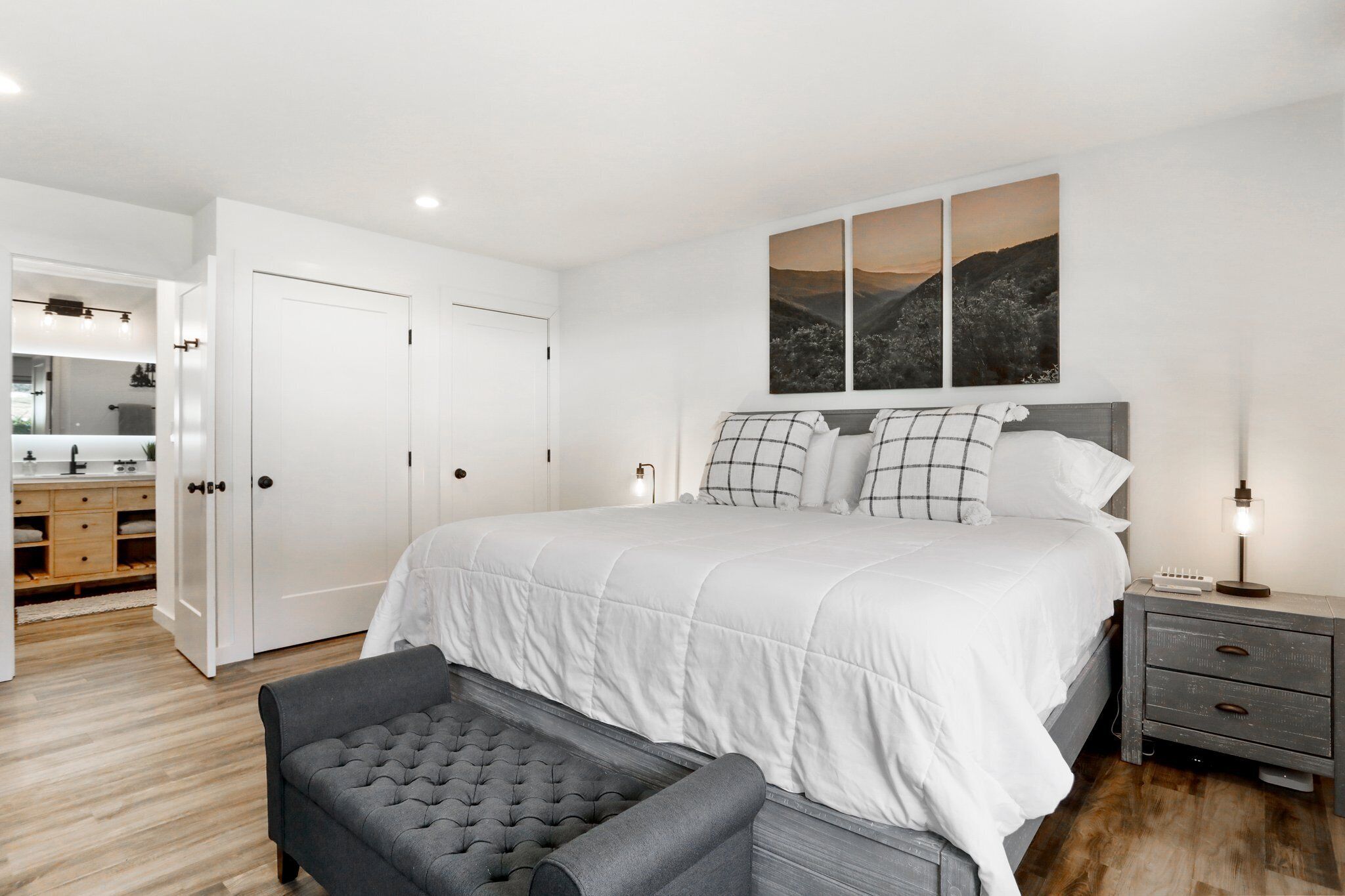 A bedroom with a large bed, a bedside table, a chair, and a wardrobe.