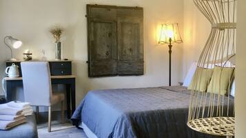 A bedroom with a bed, a desk, a chair, and a hanging chair.