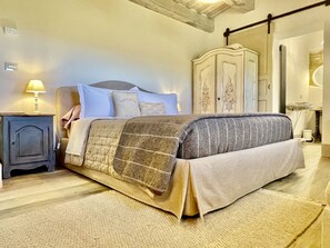 A bedroom with a bed, a nightstand, a wardrobe, and a lamp. - Vento Dorcia (Pienza)