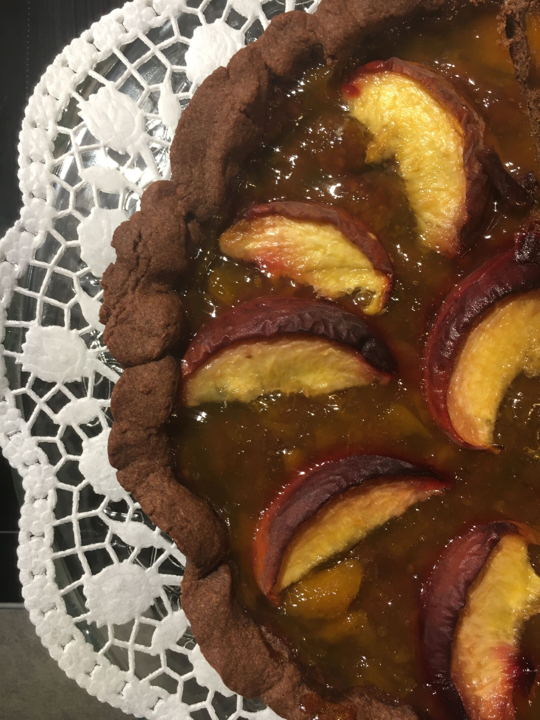 A pie with fruit slices on a lace doily.