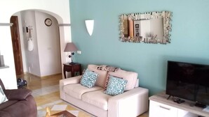 A living room with a sofa, a glass coffee table, a TV, and a lamp. - Luxurious 2 Bed Villa (Montaña Roja, Playa Blanca)
