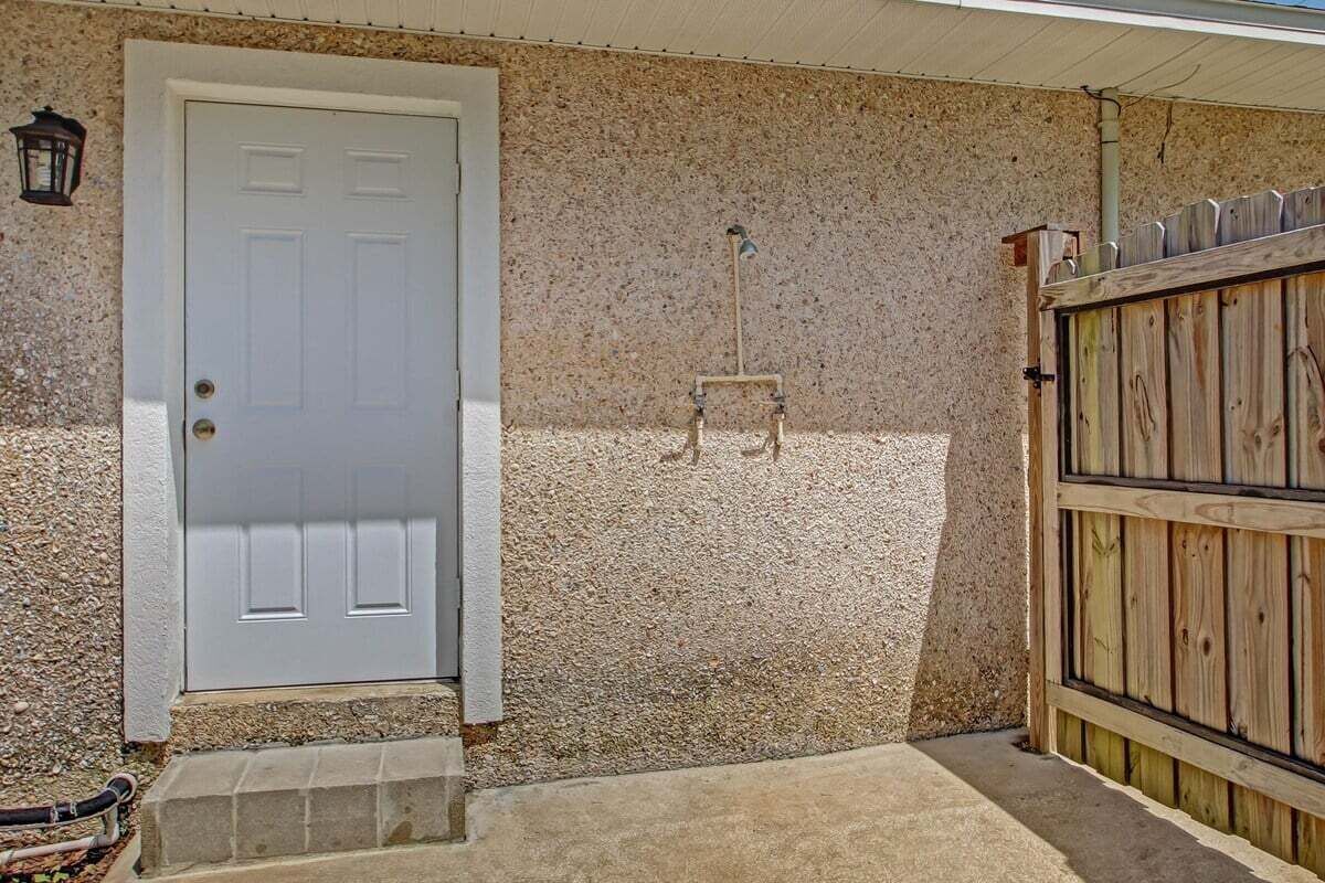 A white door with a small step leading up to it, a concrete step, and a wooden fence with a gate.