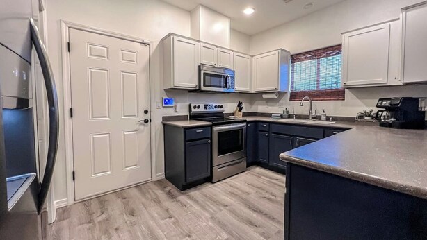 A modern kitchen with a built-in microwave, oven, and sink, white cabinetry, and a grey countertop. - Centrally Located River Home with Mountain Views! (Fort Mohave)