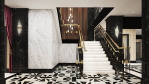 A grand staircase with a geometric patterned floor, marble walls, and a chandelier. - The LaSalle Chicago, Autograph Collection by Marriott (Chicago)