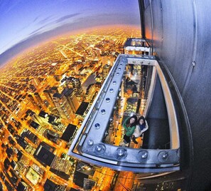 A high-altitude aerial view of a cityscape with a glass elevator.