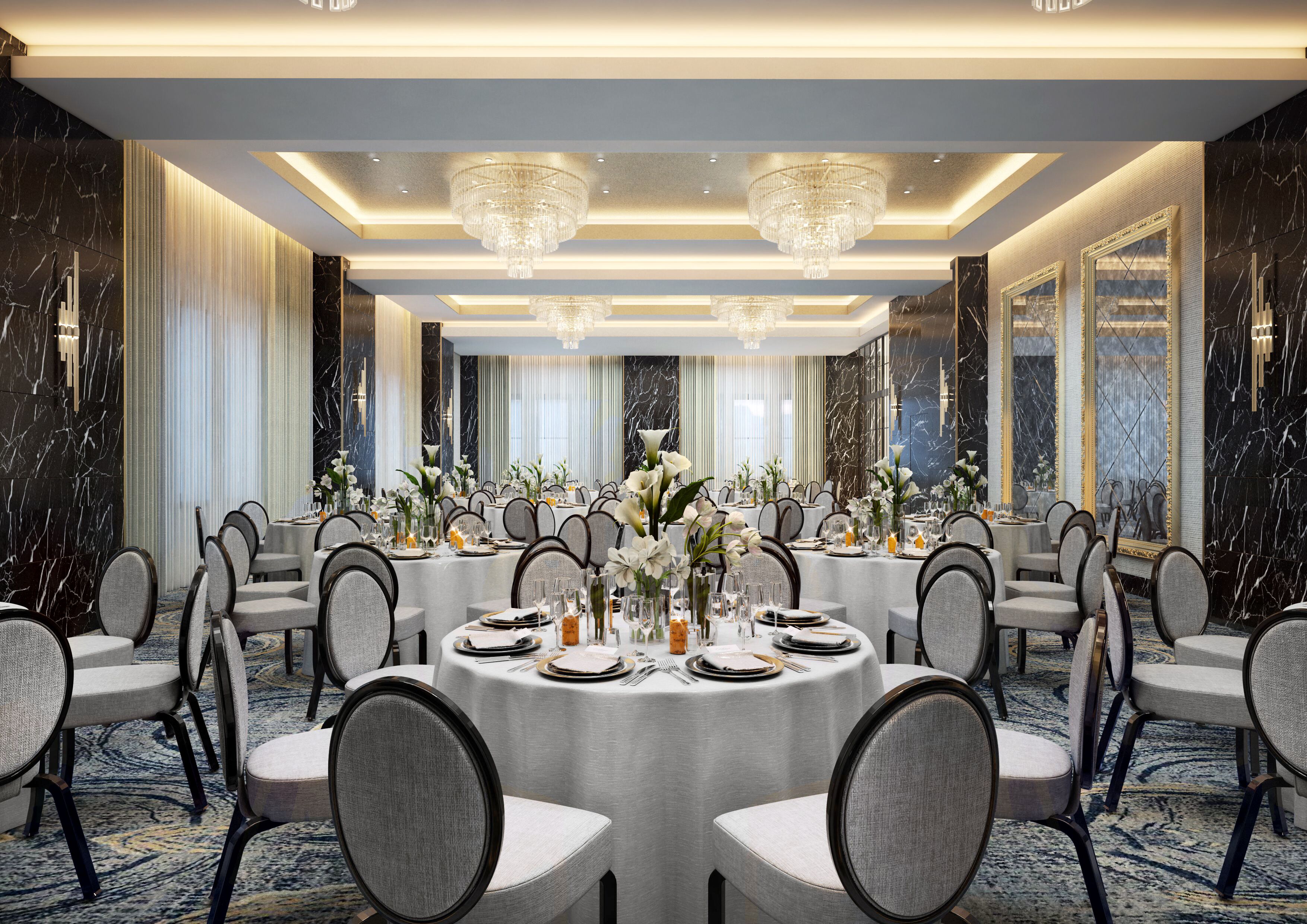 Un salón de banquetes con mesas redondas dispuestas para cenar, candelabros y paredes de mármol.
