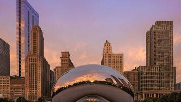 A modern glass building with a unique curved design, surrounded by other tall skyscrapers.