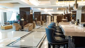 A modern hotel lobby with a bar area, seating arrangements, and a reception desk.
