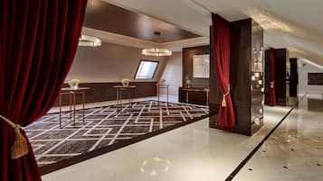 A hotel lobby with a geometric patterned carpet, a chandelier, and a large window.