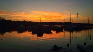 A marina at sunset with boats docked and calm water reflecting the sky. - Holiday apartment on the ground floor, with a terrace in Mediterranean greenery and air-conditioned (Klimno)