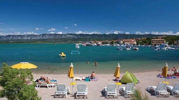 A beach with sun loungers, umbrellas, and a clear view of boats in the water. - Holiday apartment on the ground floor, with a terrace in Mediterranean greenery and air-conditioned (Klimno)