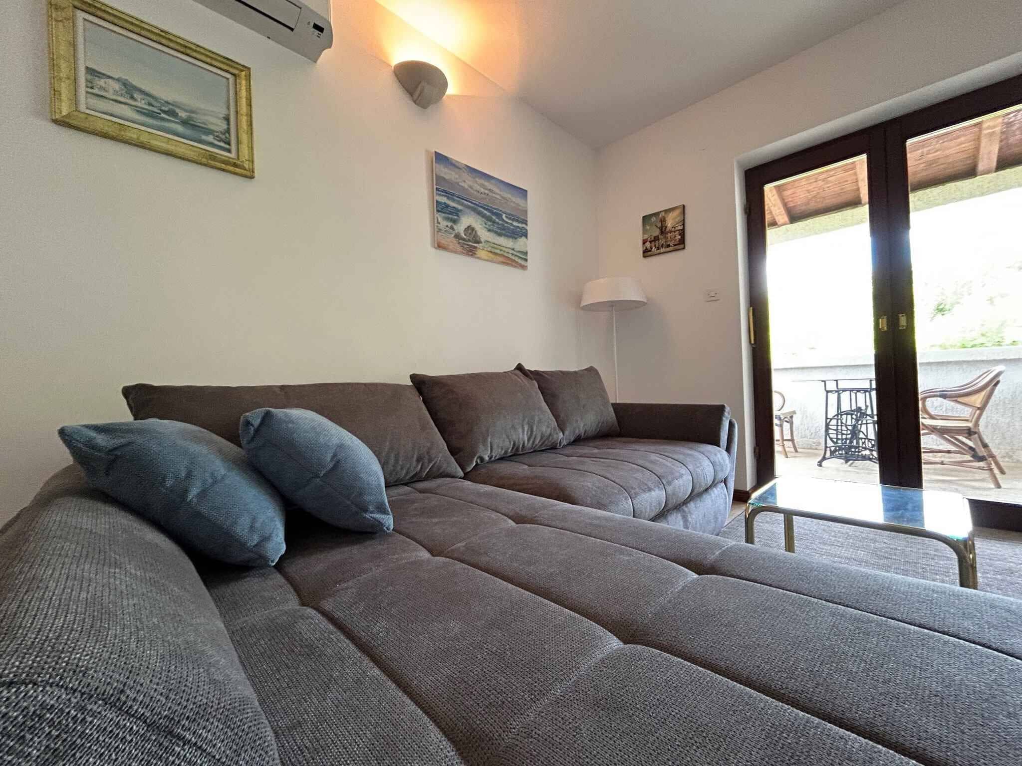 A modern living room with a large sectional sofa, a floor lamp, and a sliding glass door leading to an outdoor area.