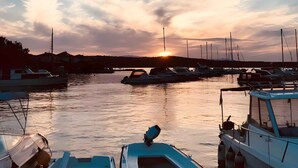 En lystbådehavn med fortøjede både, solnedgang i baggrunden og stille vand.