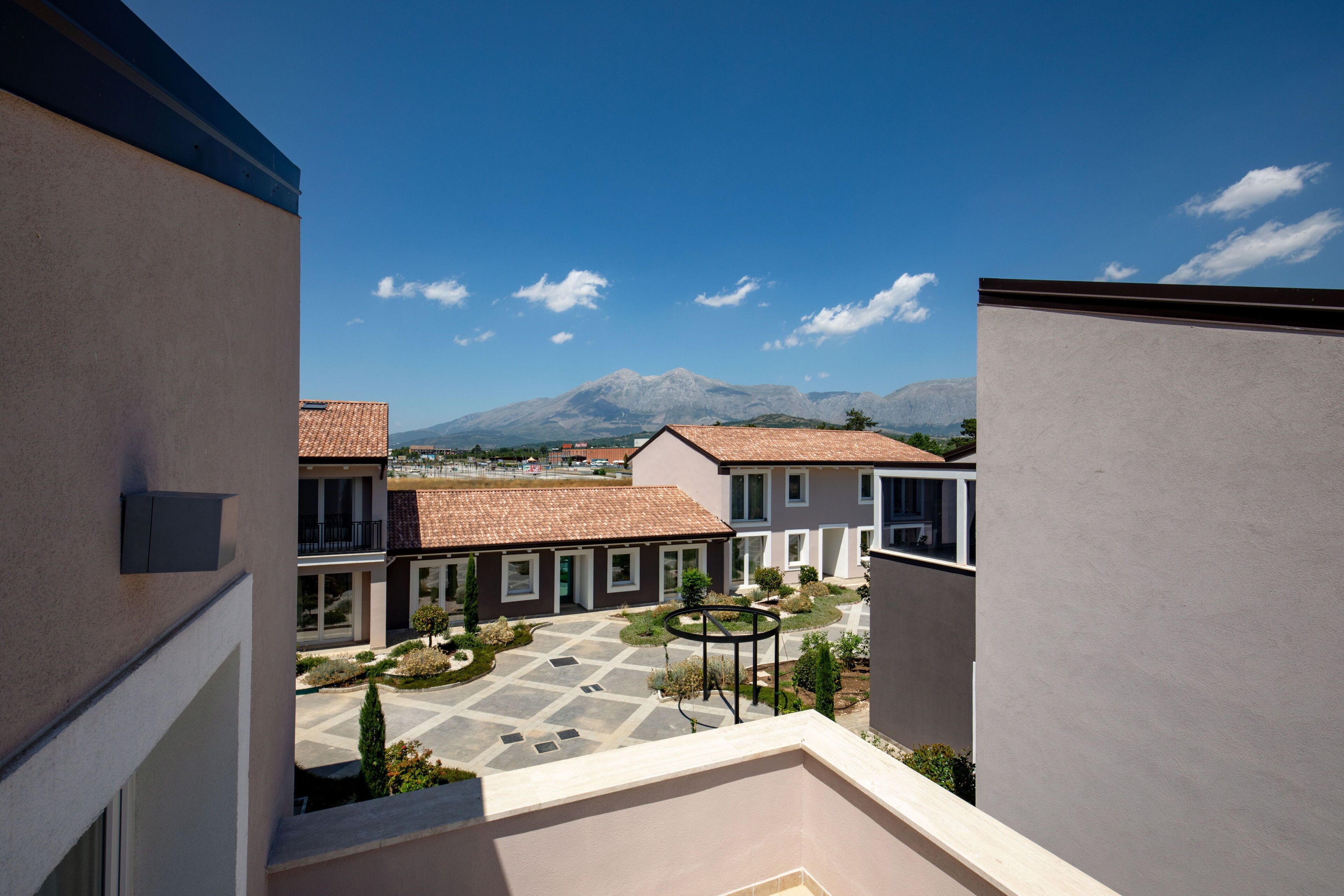 Un cortile con vista sulle montagne, circondato da edifici con tetti in tegole.
