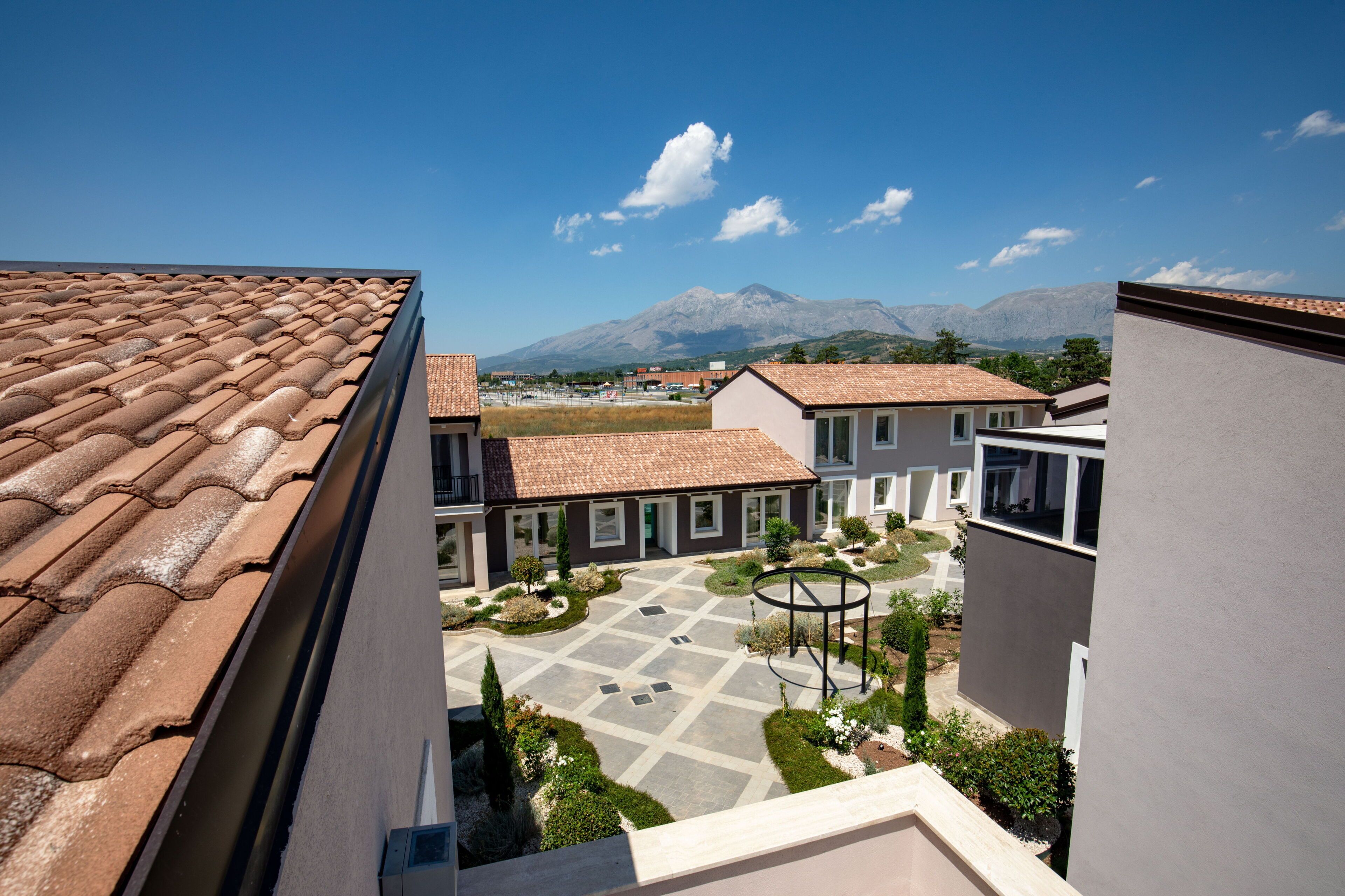 A courtyard with a tiled roof, a central garden, and buildings with a modern design.