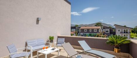 Una terraza en la azotea con sillones de descanso, una mesa y plantas en macetas.