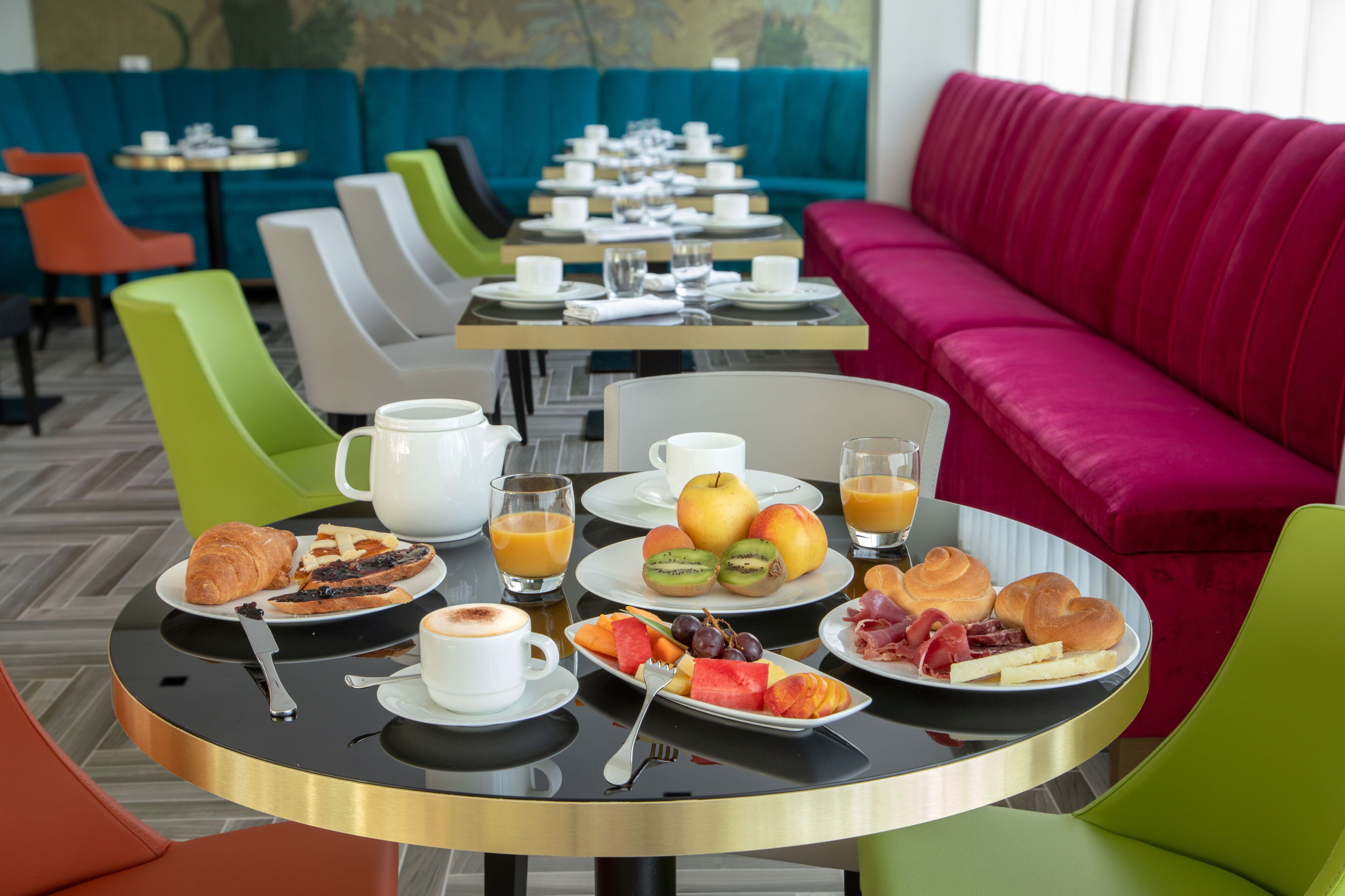 A breakfast setting with tables, chairs, and a sofa in a modern dining area.