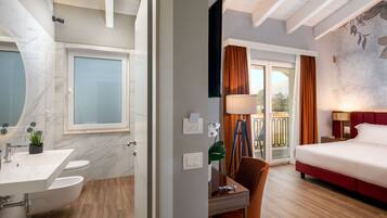 A modern hotel room with a bathroom, a desk, and a bed.