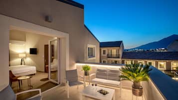 Un balcon avec des meubles blancs, une plante en pot et une table avec des verres à vin.