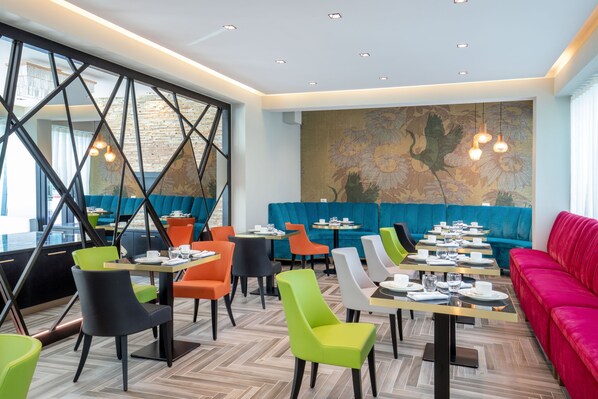 A modern restaurant with vibrant seating, a large mural, and a mix of table and booth seating. - Hotel Della Piana (Avezzano)