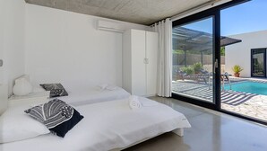 A modern bedroom with two beds, a large sliding glass door leading to a pool area. - Villa Marcelino with Private Pool and free A/C near to Port de Pollensa (Puerto Pollensa)