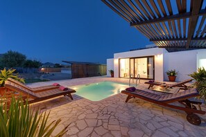 Un espace piscine avec des chaises longues et une pergola.