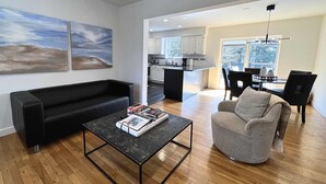 A modern living room with a black sofa, a grey armchair, and a black coffee table. - BlackBerry Private home with jacuzzi yearlong (East Hampton)